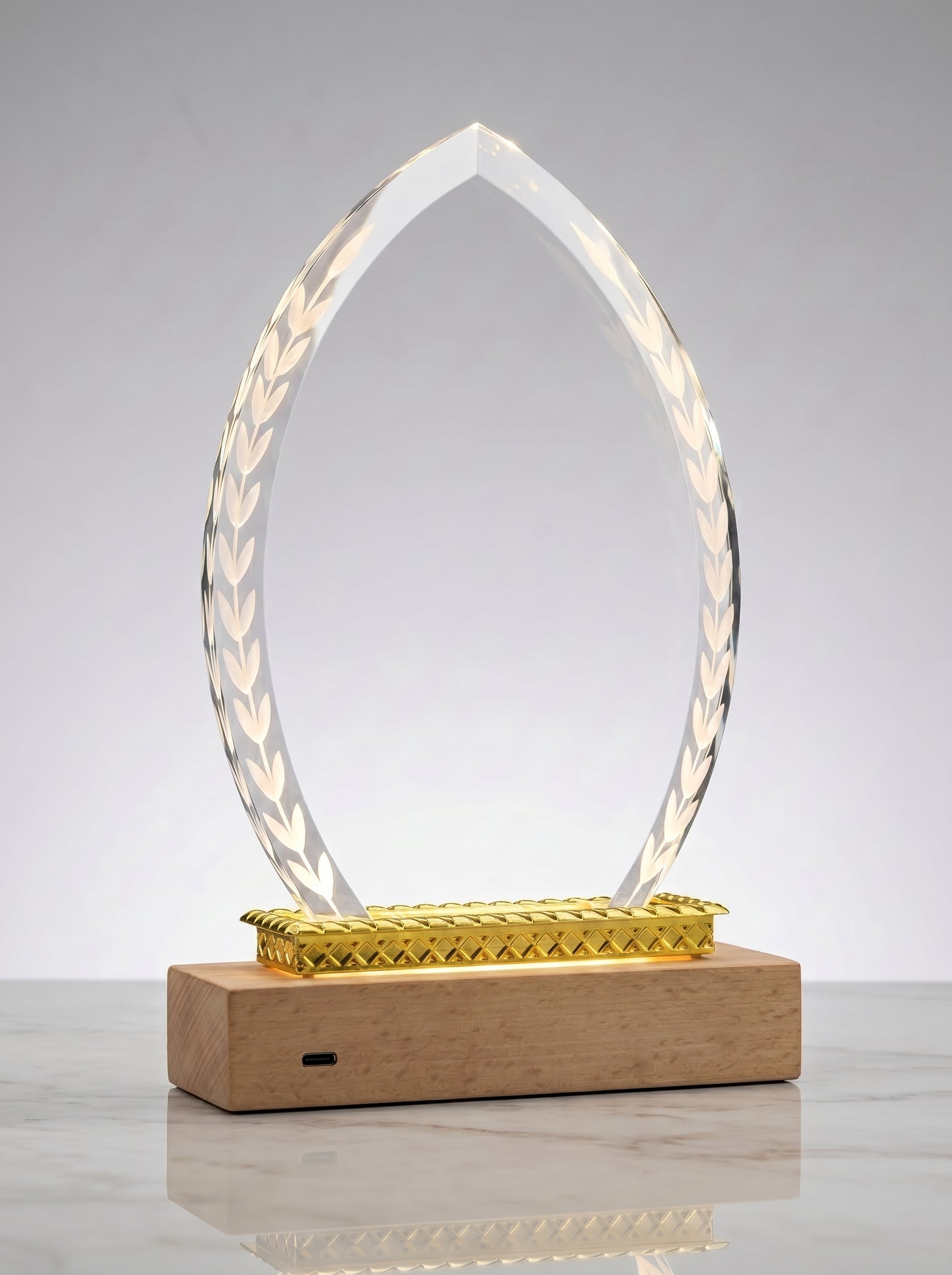 Trophée en verre lumineux pour bureau ovale avec lauriers et base en bois clair, idéal comme récompense entreprise personnalisée.
