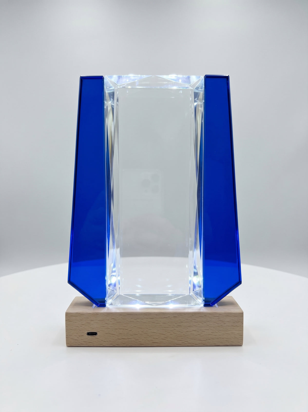 Trophée verre lumineux à facettes biseautées avec ailes bleu cobalt sur socle bois éclairé.
