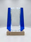 Trophée verre lumineux à facettes biseautées avec ailes bleu cobalt sur socle bois éclairé.
