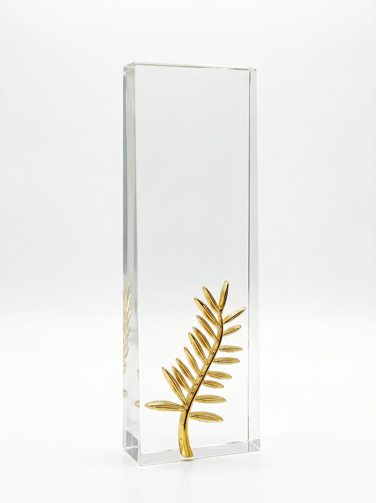 Trophée en verre personnalisé avec motif palme dorée posé sur un bureau moderne